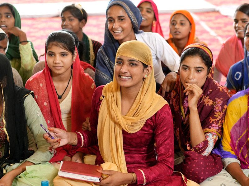 group of ten young women sitting on the floor, smiling